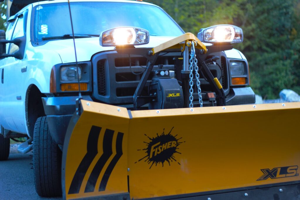 Snow Plow Bros truck with plow mounted, headlights on